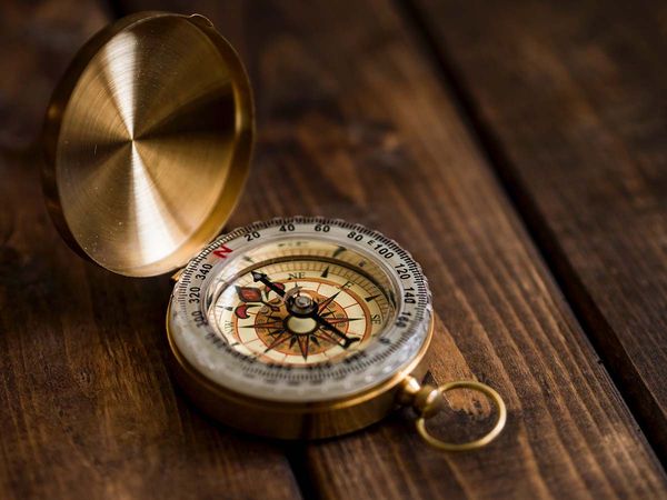 A golden compass sitting open on a wooden surface