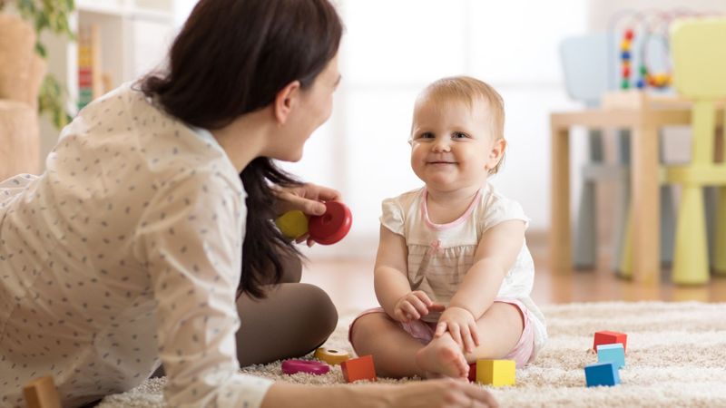 daycare worker playing with blocks with baby