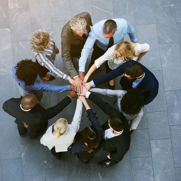 a group of employees with their hand in a pile