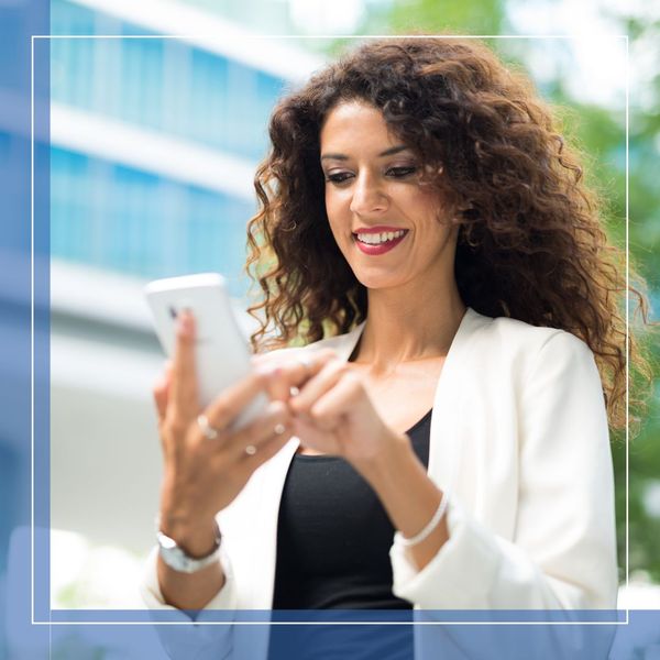 woman smiling while looking at her phone