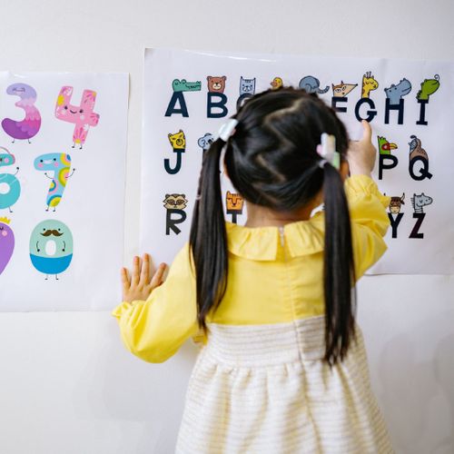 Young girl pointing at the letter "g."