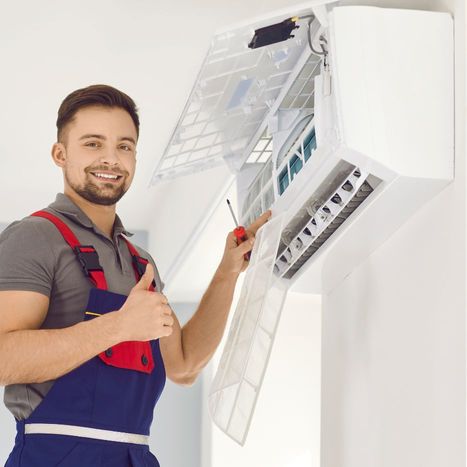 Smiling AC technician giving a thumbs up next to an AC unit 