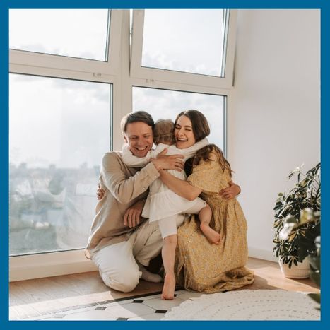 A happy mother and father hugging their young daughter indoors