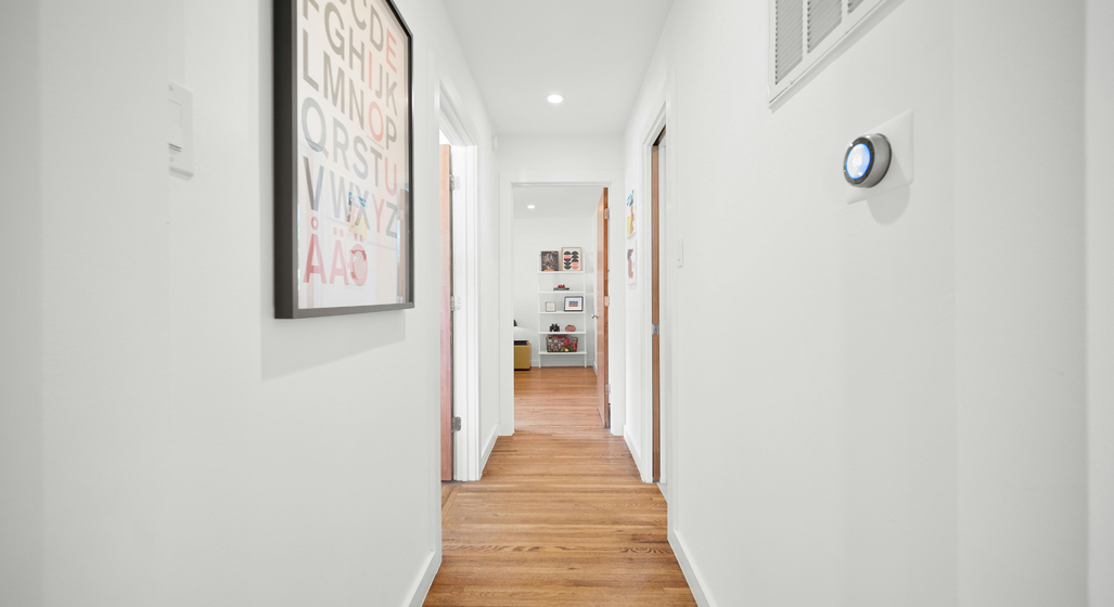 A hallway of an apartment or home with a modern thermostat on the wall