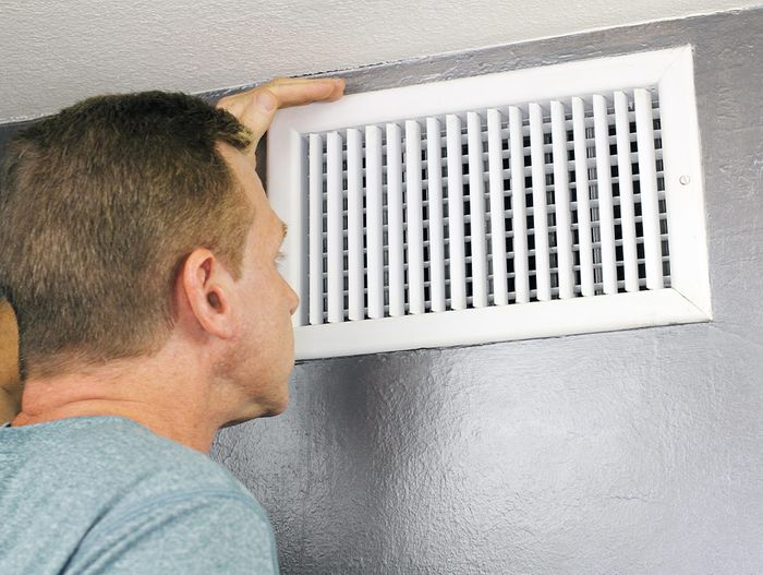 a person inspecting a heating vent