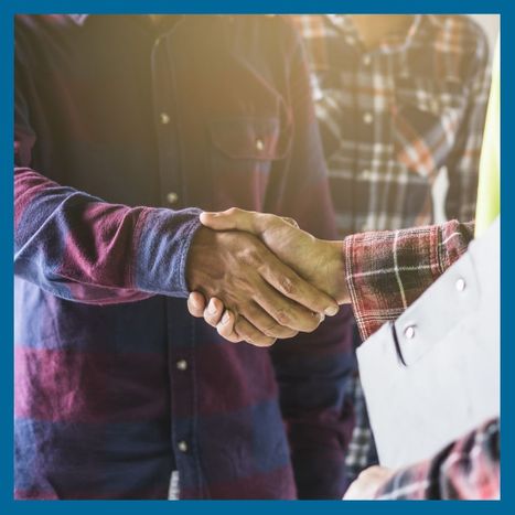 A contractor holding a clipboard and shaking hands with a customer