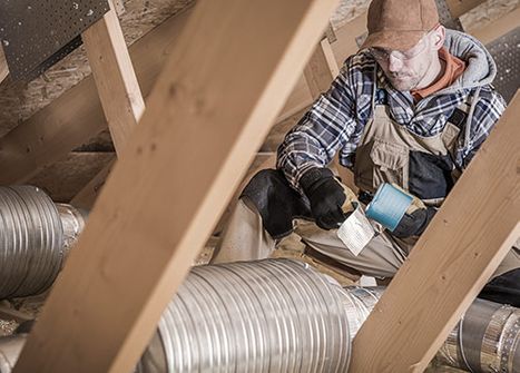 A man does HVAC work in an attic