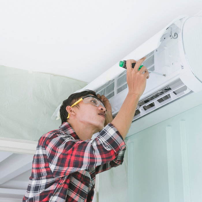 An HVAC tech using a screwdriver on a mini split