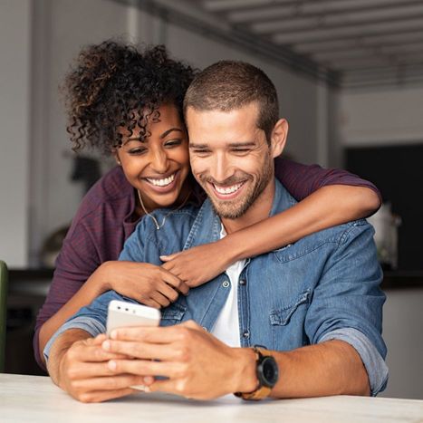 A happy couple booking an HVAC service on their phone