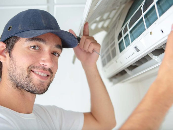 Man smiling while installing an AC unit