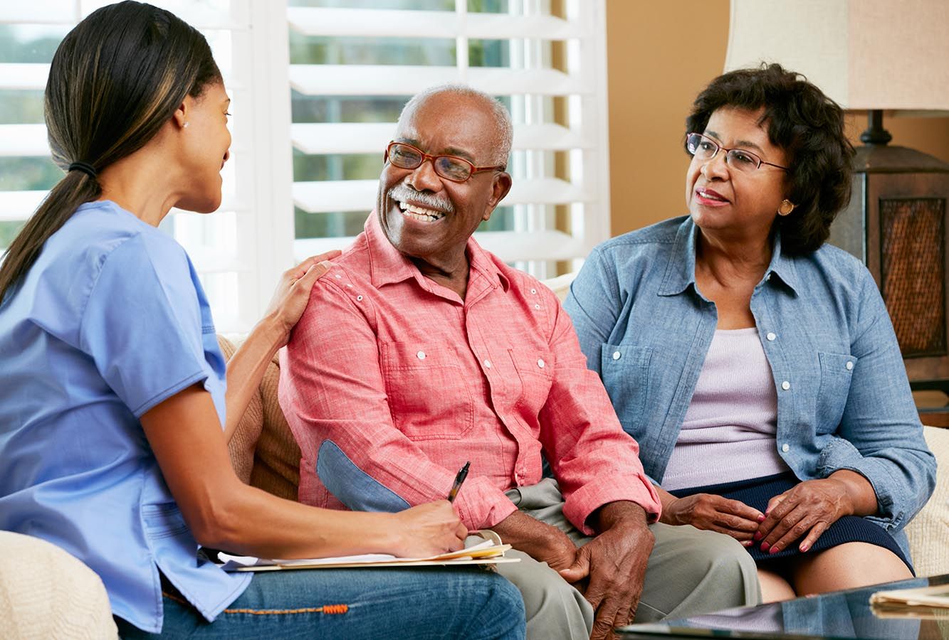 smiling nurse talking with elderly couple