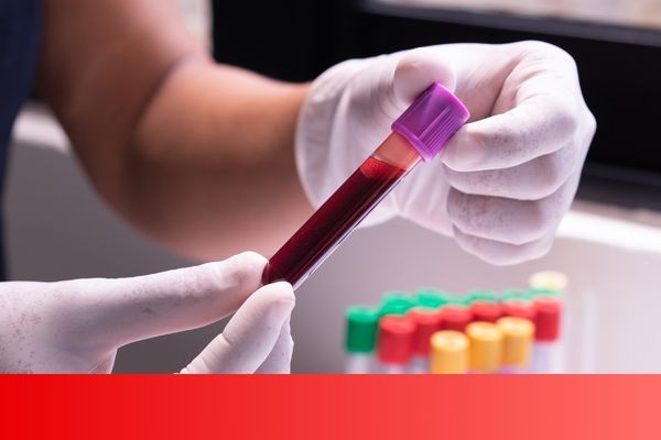 holding a vial of blood