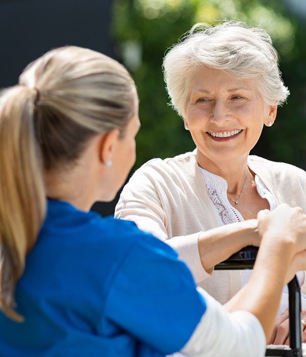 nurse talking to a smiling senior woman in a wheel chair