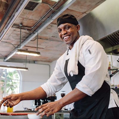 Chef smiling as he cooks in a commercial kitchen space.