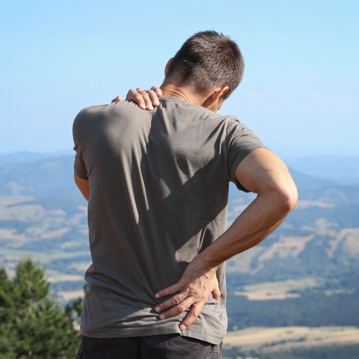 man suffering from back pain while hiking