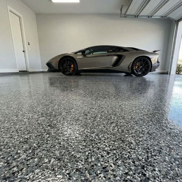 modern garage with a beautiful, reflective, speckled epoxy floor and a luxury car parked inside