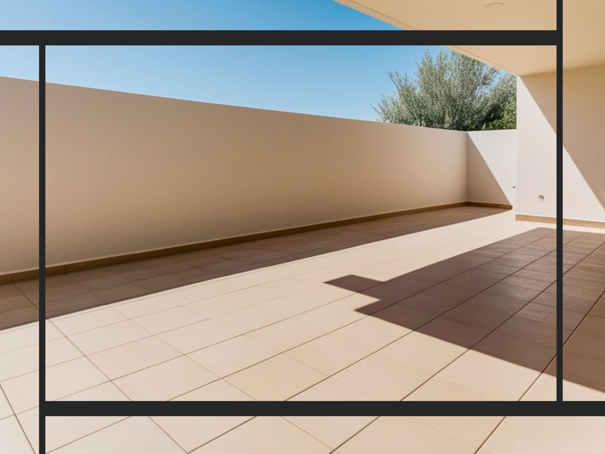 A wide-angle view of a spacious outdoor patio or balcony featuring clean, tan ceramic tile flooring and a minimalist white privacy wall