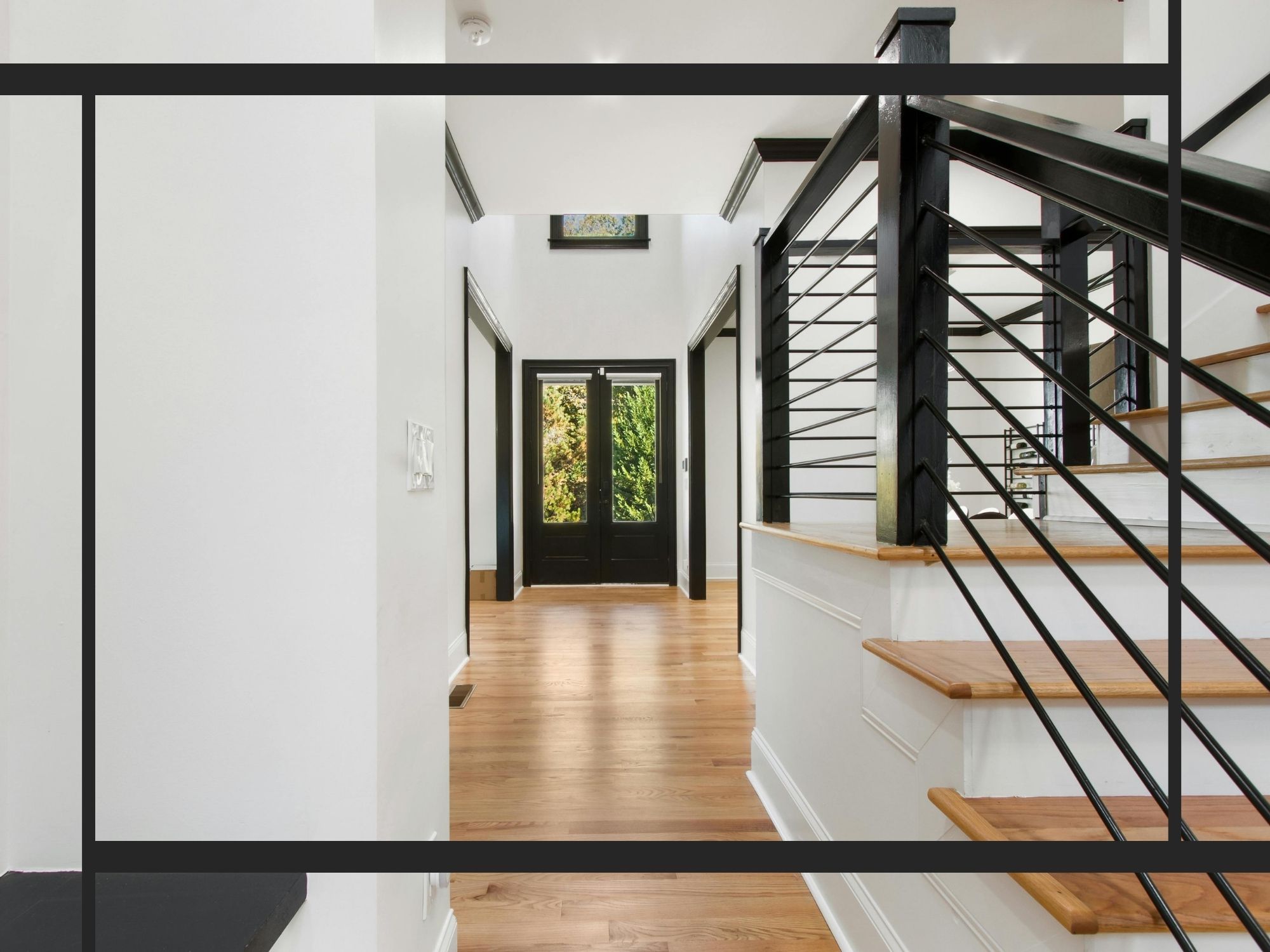 A sophisticated home entryway with light hardwood floors, high ceilings, and a modern staircase featuring black metal railings and sleek white trim.