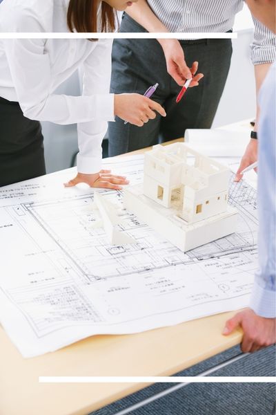 A professional architectural planning session showing a team discussing technical blueprints