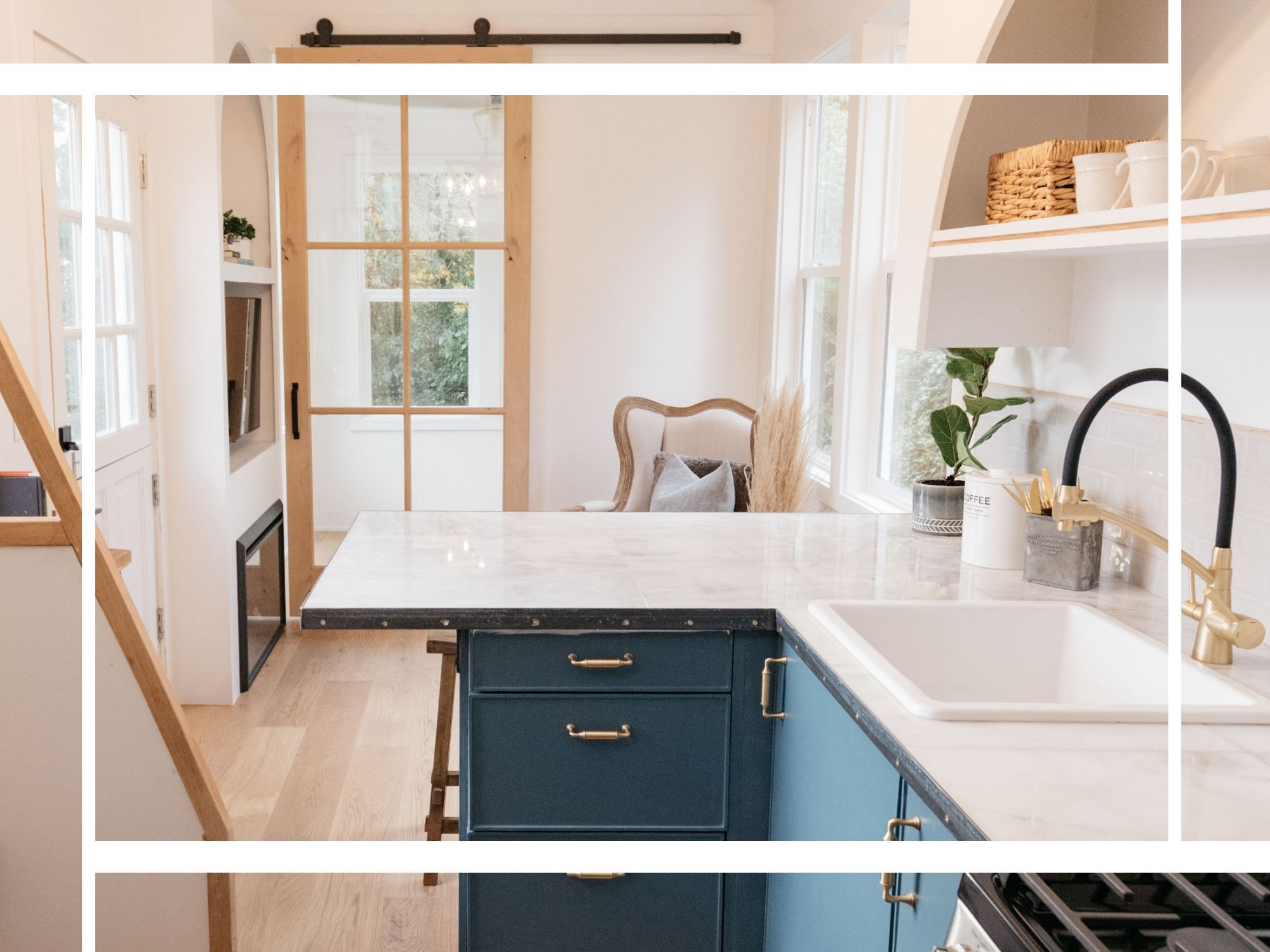 The interior of a modern tiny home featuring a teal kitchen island with a marble countertop, gold hardware, and a sliding barn door