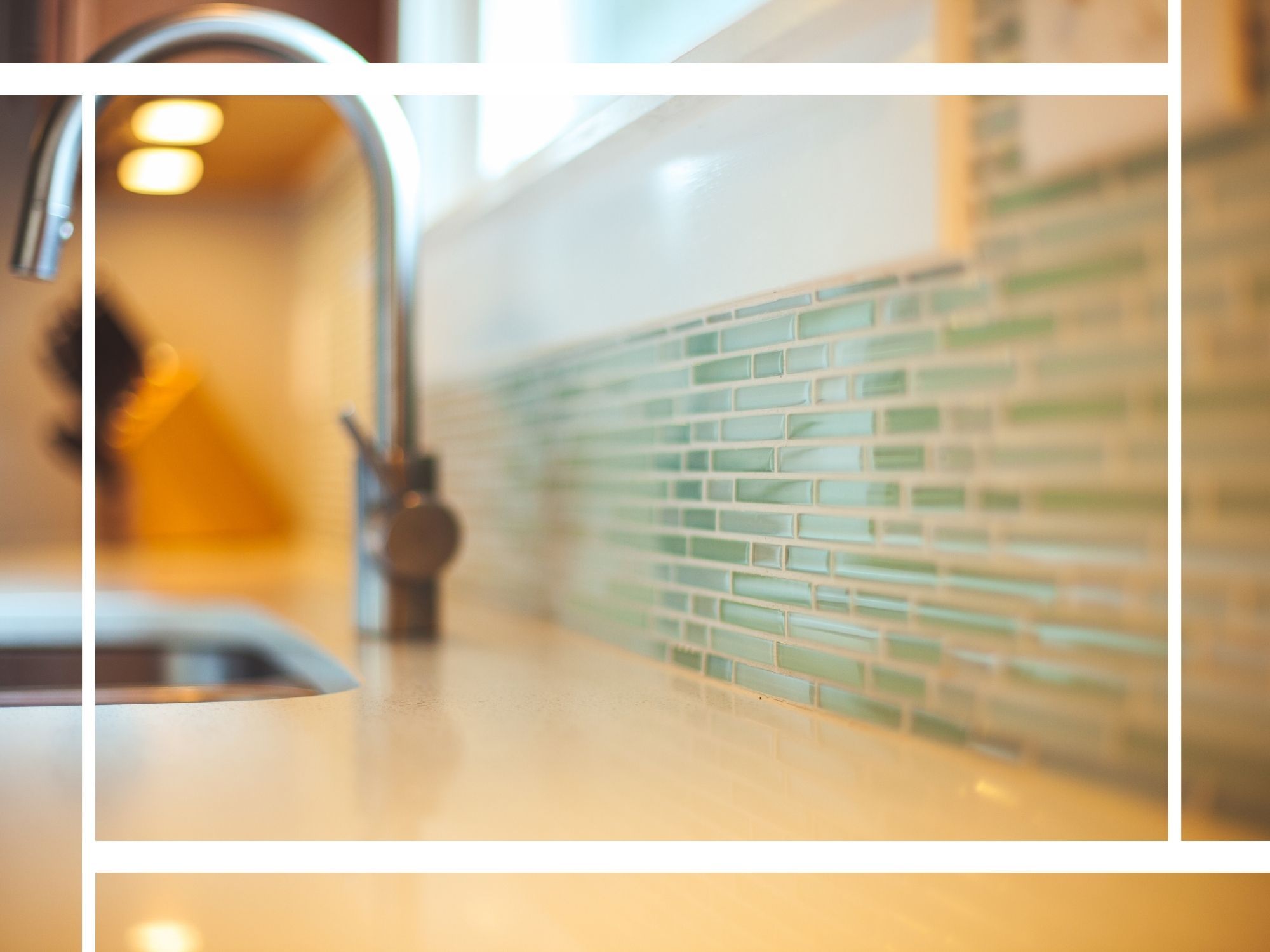 A close-up, shallow depth-of-field shot of a modern kitchen’s white quartz countertop and a light green glass mosaic tile backsplash, featuring a brushed nickel faucet in the background.