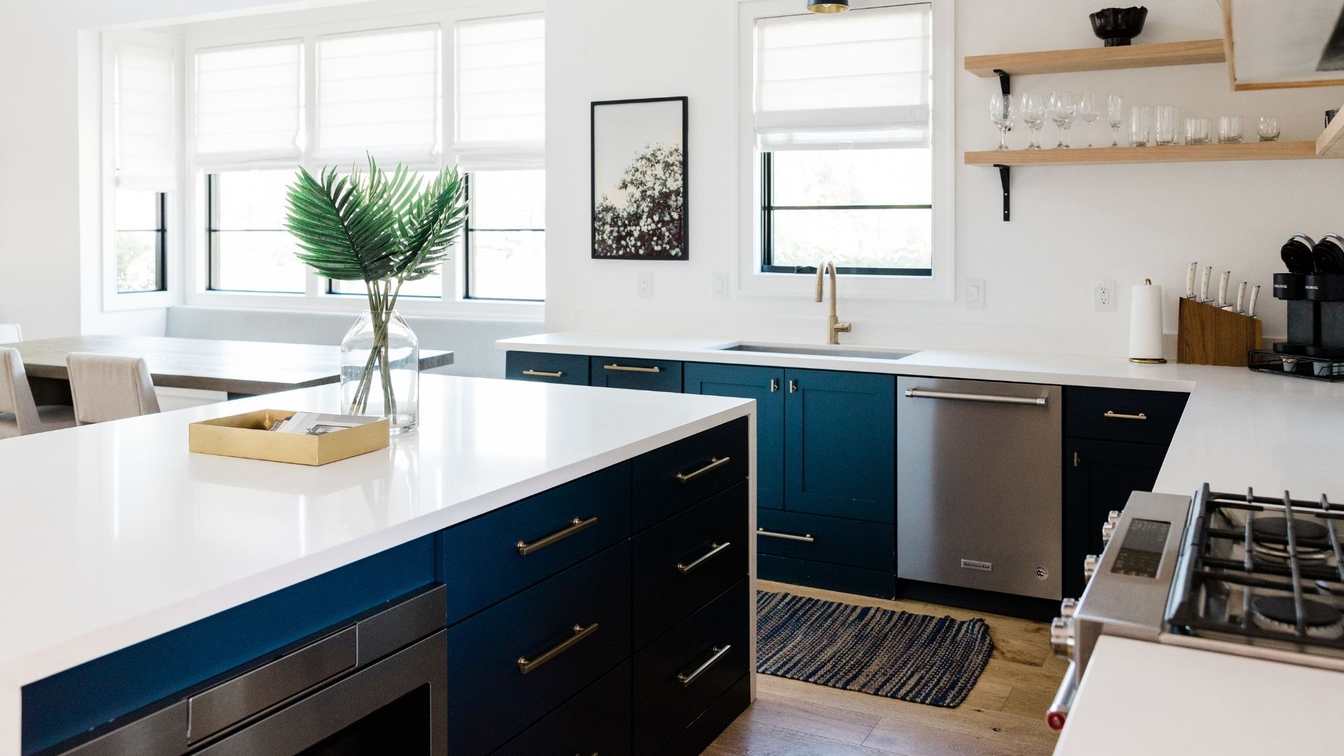 gourmet kitchen featuring a navy blue island with white quartz countertops, gold hardware, and open wood shelving