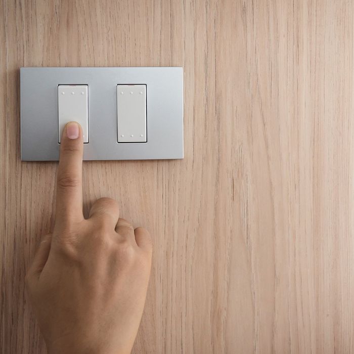 Person putting their finger on a lightswitch to turn it off