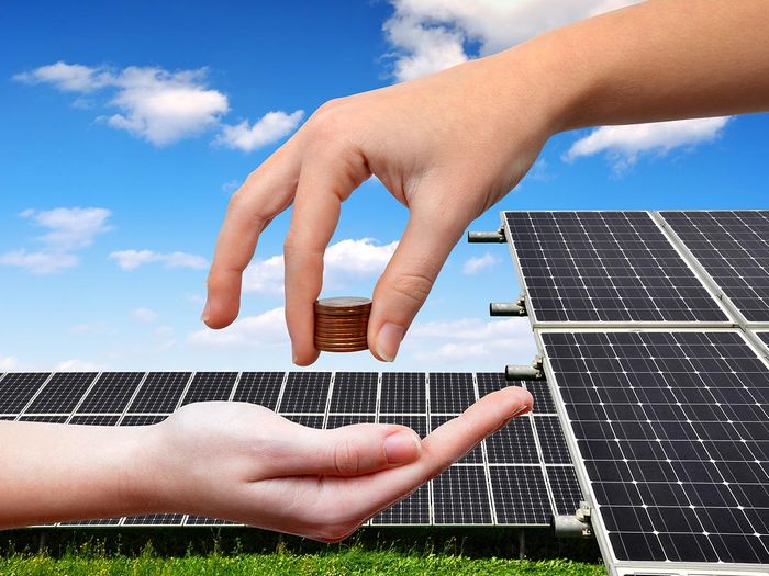 Solar panels and coins in hand