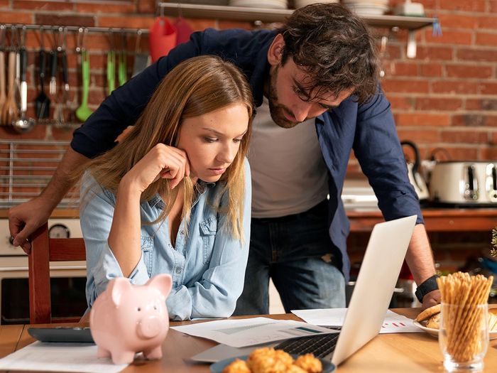 Couple looking over bills with a calculator and a piggy bank
