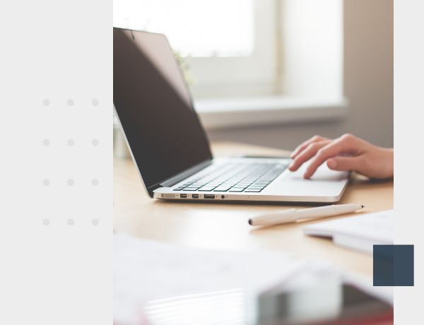 laptop sitting on desk with pen next to it