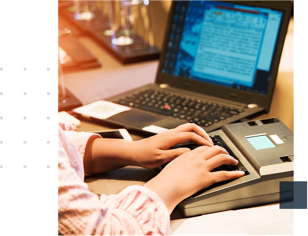 a person typing on an electronic stenography machine 