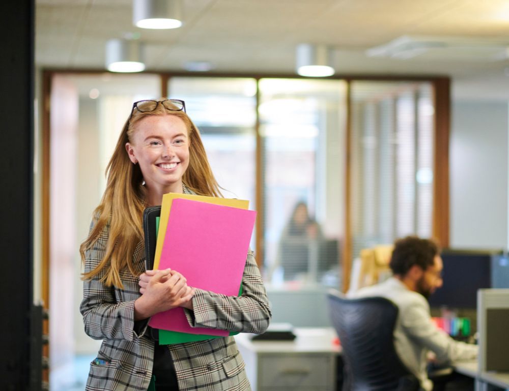 woman walking through an office carrying files