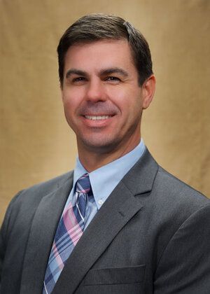 Jeff Martin, financial advisor in Arizona, wearing a gray suit and striped tie, smiling in front of a neutral background. Jeff Martin Financial Advisor Arizona