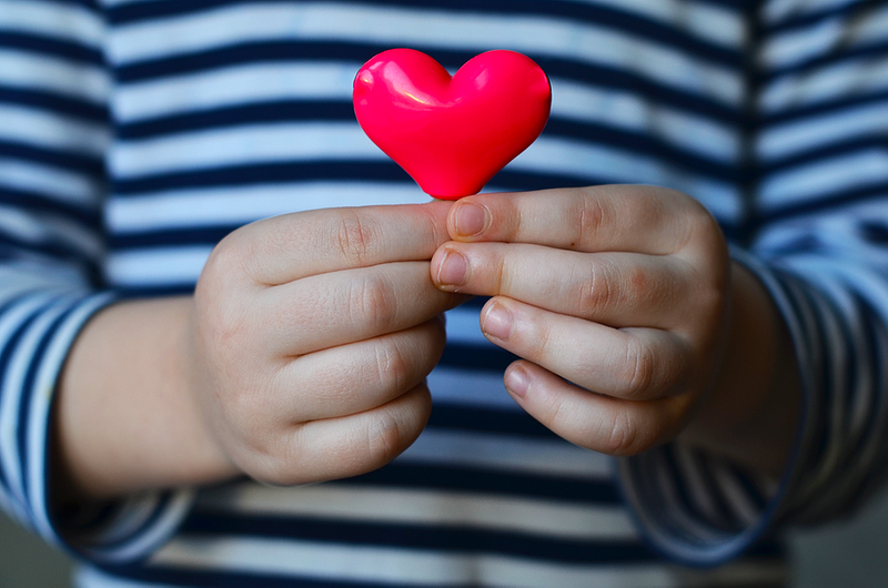 Child Holding a Red Heart-Shaped Object