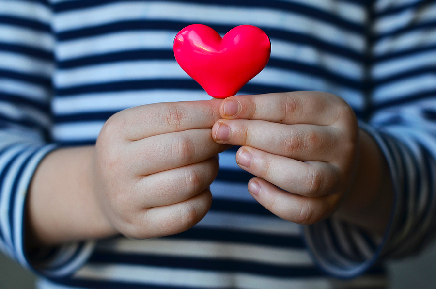 Child Holding a Red Heart-Shaped Object