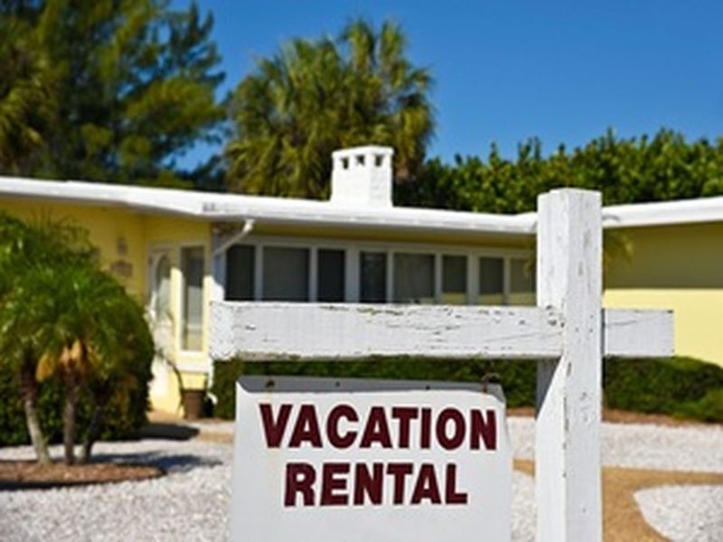 Vacation rental home with a white wooden sign out front, representing short-term rental property investment — J. Martin Wealth Management, Arizona Vacation rental home with for-rent sign