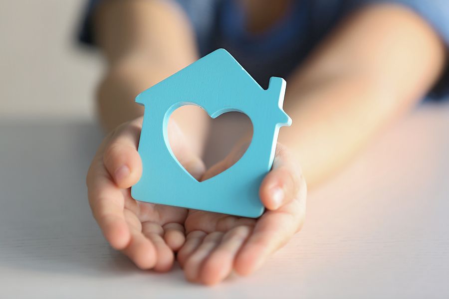 Hands Holding Blue House with Heart – Adoption Process