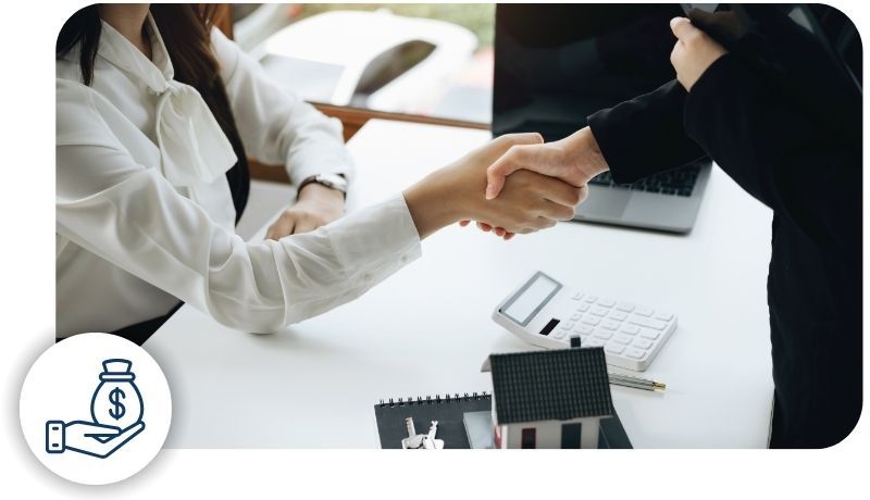 two people shaking hands with a model home, keys and a calculator on the desk below them