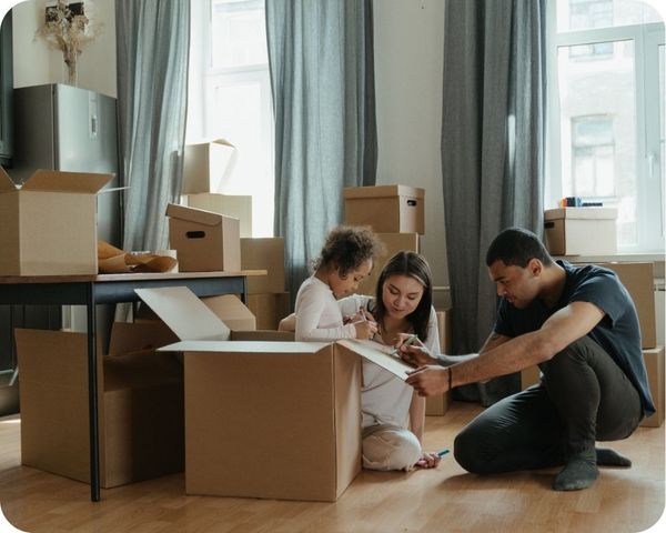 couple and child sits on floor with moving boxes and writes on box Douglas County 2.jpg