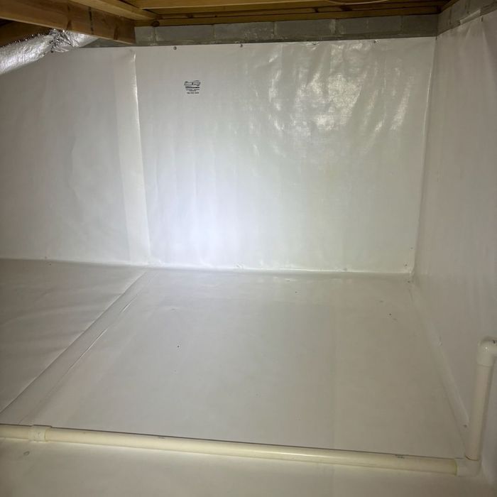 A pristine, fully encapsulated crawl space features white vapor barriers on the floor and walls A pristine, fully encapsulated crawl space features white vapor barriers on the floor and walls