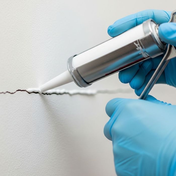 A close-up of a person sealing a small crack