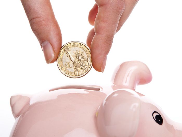 Image of a person putting money in  a piggy bank
