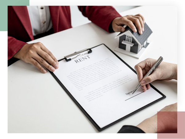 A real estate professional and a tenant are signing a formal lease agreement document to ensure legal compliance.