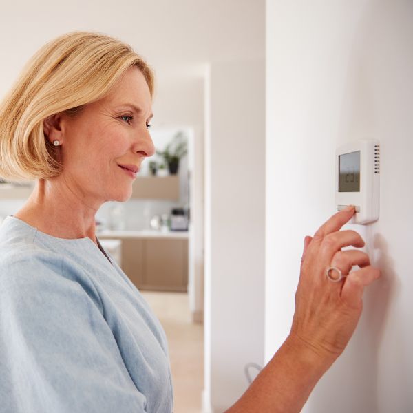 Woman adjusting her thermostat. Why Is My AC Running but Not Cooling3.jpg