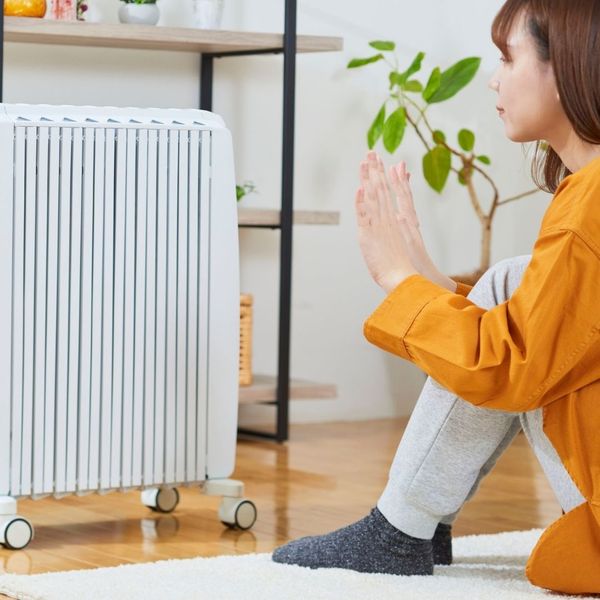 woman sitting beside a space heater