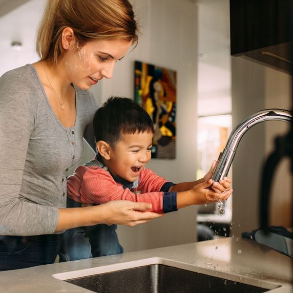 mother and sun washing hands in the kitchen