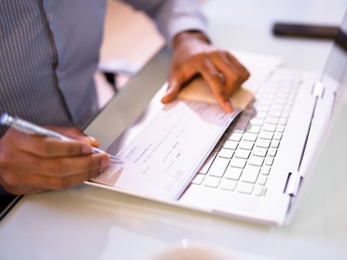 someone signs a business check in front of a laptop Tallahassee 3.jpg