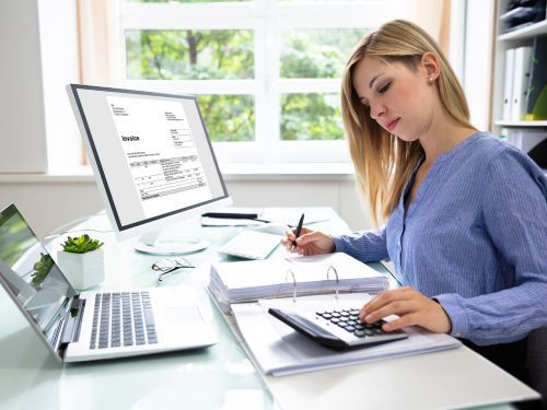 accountant uses a calulator at a desk with statements on computer screens Cairo 1.jpg