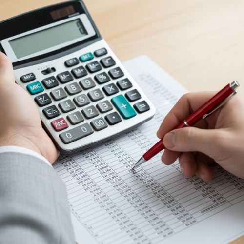 A close-up of hands using a calculator and pointing out a detail on a financial ledger, symbolizing error reconciliation.