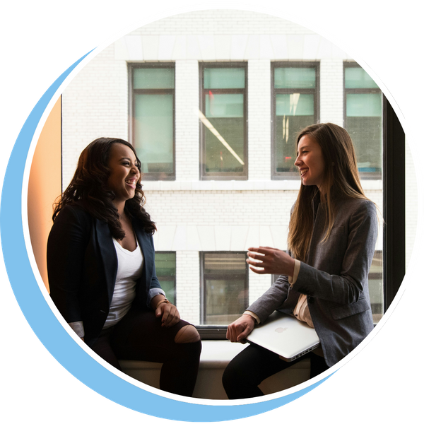two coworkers sitting in window sill talking